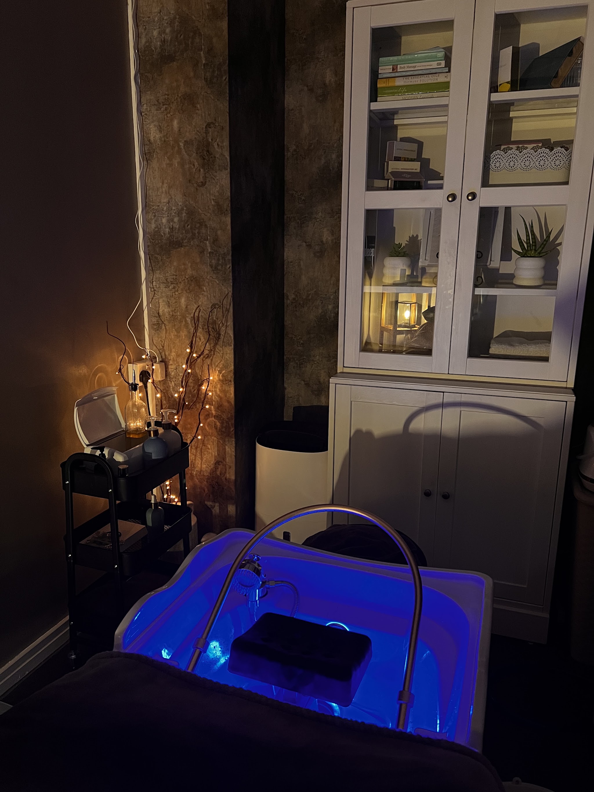 The head spa bed at night with its blue-lit basin and a glass cabinet behind