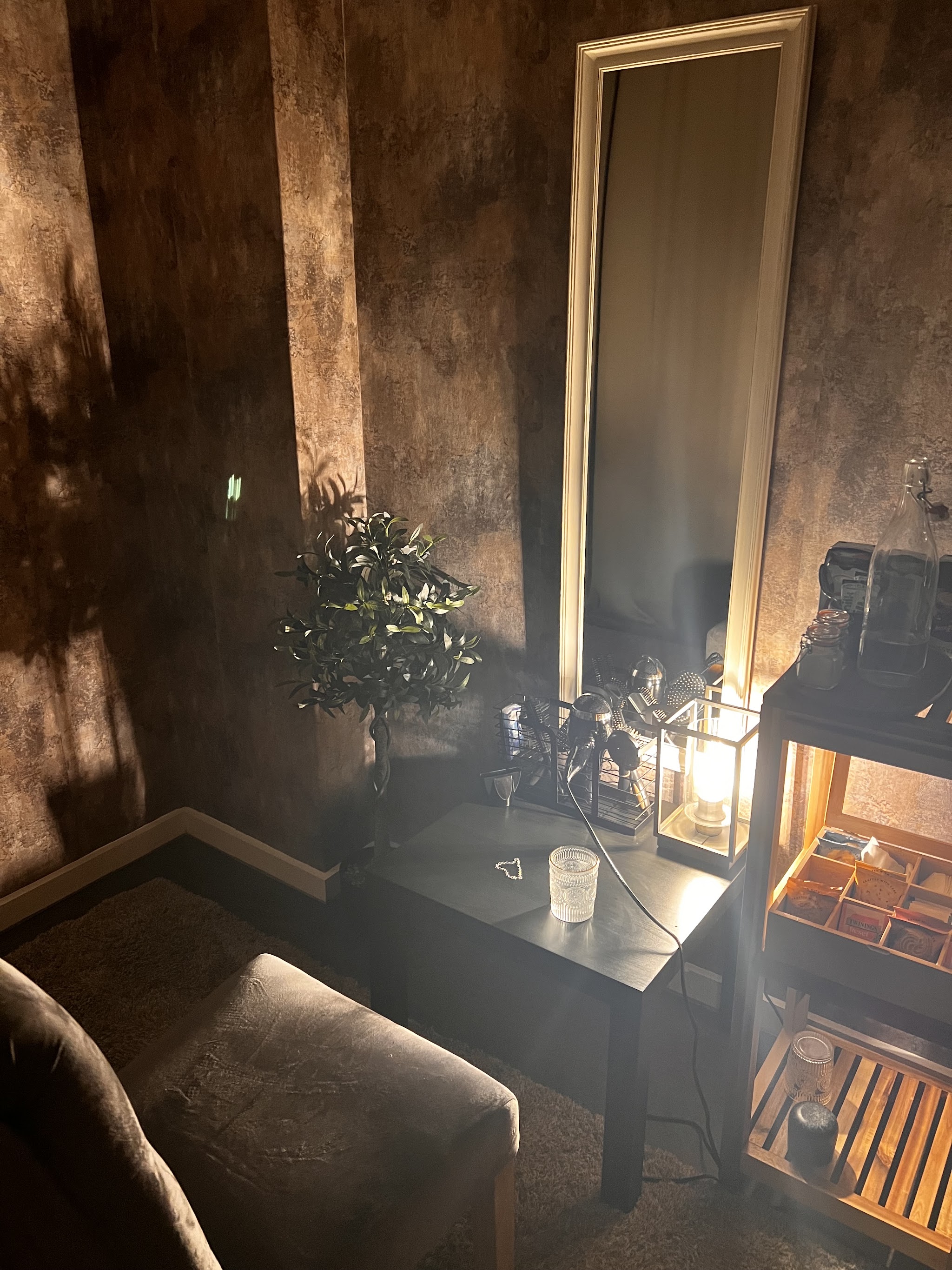 A candle-lit corner of the treatment room with a lantern, plants and a tall mirror